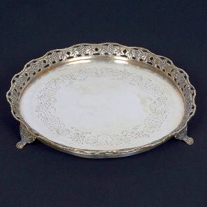 <b>Salva </b>circular em prata, apresentando fundo gravado com folhas e cachos de uvas. Borda recortada vazada com os mesmos motivos. Pés em garras. Diâm. 22 cm