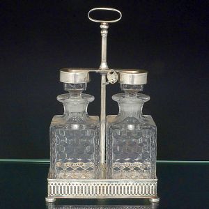 <b>Licoreiro </b>em metal prateado com duas garrafas em cristal lapidado com padrão geométrico em relevo e tampas também em metal. Apresenta marca Corbin, USA.