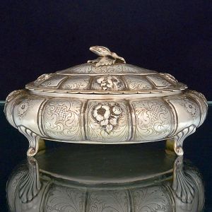 <B>Caixa</B> de forma oval em prata 800 ml. Apresenta decoração com lavrados e flores e volutas sobre gomados. Marca no verso. Compr. 21 cm. Peso 375 gramas.