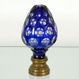 <b>Pinha </b>em cristal francês no formato do fruto, ornamentada em "overlay" azul safira e facetas circulares. Base em bronze polido. Séc. XIX. Alt. 19 cm