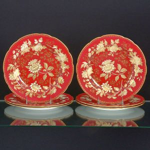 <b>Conjunto de 6 pratos </b>em porcelana inglesa Wedgwood ricamente decorados com composições floridas a ouro sobre fundo vermelho grená. Diâm. 27 cm