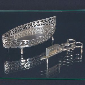 <B>Tesoura espevitadeira e seu berço </B>de forma navicular com vazados, em prata aparentemente sem marcas. Séc. XIX. Compr. 18 cm. Peso 225 gramas.