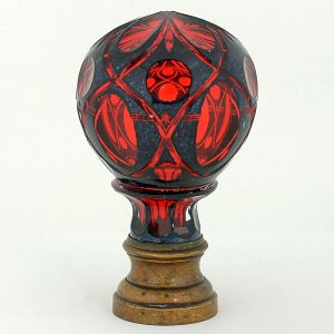 <B>Pinha </B>globular francesa em cristal rubi com "overlay" em negro. Lapidada com estilizações. Base em bronze. Séc. XIX. Alt. 18 cm