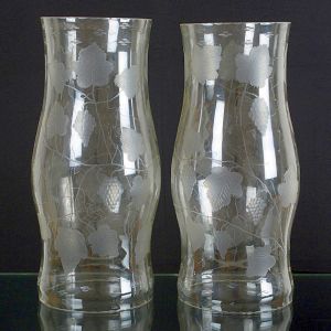 <b>Par de donzelas </b>em cristal expandido ao centro e decoração em "satiné" com cachos de uvas e folhas de parreira. Alt. 50,5 cm