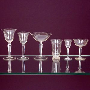 <b>Serviço de copos</b> em vidro cristalizado, apresentando lavrados com flores, haste facetada e bases circulares. Constando de 11 taças p/ água (alt. 16,5 cm), 11 taças de champanhe ou Martini, 12 taças p/ vinho, 11 copos p/ aperitivos, 12 taças p/ licor e 12 taças menores p/ "drinks". Total 69 peças.