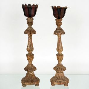 Antigo <b>par de tocheiros </b>em madeira patinada, no estilo Brasil colônia, entalhados com folhagens e perolados. Bocais em latão. Um apresenta pequeno quebrado. Alt. 52 cm