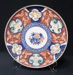 IMARI - prato em porcelana japonesa com rica decoração sobre fundo rouge de fer nos tons azul cobalto e  ao centro ramo de flores. Marcado na base. Diâmetro de 24 cm.