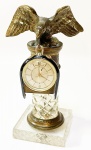 Bela escultura de águia em bronze cinzelado sobre coluna de cristal lapidado arrematada em aro de bronze sobre base quadrada de resina. Acompanha relógio despertador suiço "Jaeger Le Coulthe" sem garantia de funcionamento. Coluna mede 14 cm. Obs: base compequena trinca interna.