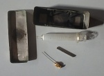 Colecionismo - Antiga Seringa ambulatorial de vidro com agulha e protetor de agulha acondicionada em seu estojo prateado. Med. 11x3,5x2,5cm