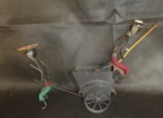 Brinquedo antigo feito de ferro com dois(2) bonecos  e uma carruagem. Sendo que um puxando a carroça e outro sentado com uma vara de pescar. No estado Med.22 x 28cm