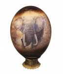 COLECIONISMO- Exclusivo e artesanal ovo de avestruz vindo da África. Decorado com majestosa imagem de um elefante na selva, assente em base cilíndrica de metal dourado. Medida 20 cm de altura. Em bom estado, enobrece qualquer coleção.