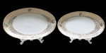 PORCELANA- Duas travessas  em porcelana branca com borda  perolada e decorada com guirlandas de flores em policromia e farta douração. Da manufatura REAL S.PAULO MADE IN BRAZIL.  Medida 23,5D. Em bom estado, com mínimas marcas de uso e um pequeno bicado em cada uma delas.