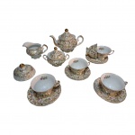 Guarnição para chá em porcelana Schmidt decoração de singelas flores e dourado sobre fundo branco composto de 1 bule, 1 cremeira, 1 açucareiro, 1 manteigueira, 4 xícaras e 4 pires, a 16 x 13 a 13 x 10 cm.