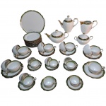 Guarnição para chá e café em porcelana Renner com frisos verdes e dourado sobre fundo branco,  marcados na base, composto de : 1 bule para café, 1 bule para chá, 1 cremeira, 1 açucareiro, 11 xícaras para chá e 10 xícaras para café, Alt. 22, 12, Alt. 22 a Alt. 15, Diam. 16 cm. Total: 25 peças.