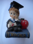Colecionismo - Peça em resina representando um UNIVERSITÁRIO, sentado em um livro de TEACHER (Professor) - Dimensões 6,5 cm de altura - 5 cm de largura e 5 cm de comprimento. Fabricação e procedência dos Estados Unidos.- Muito bom estado de conservação. 19