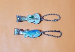 Antigo conjunto de cortadores de unha no formato de violão e peixe, sendo às figuras em resina acrílica policromada e tons dourados - Marca Olympic, anos 70 - Dimensão de cada sem a corrente: 4,5 cm