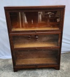 Estante livreiro secional de três nichos,  estilo advogado, produzida pela CJ Lundstrom Manufacturing Company. Little Falls, Nova York, início do século XX. São três módulos de encaixe; Portas basculantes. Madeira Carvalho. Marcas de uso.  Medindo 113 x 28 x 85.5 cm