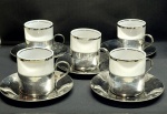 Conjunto de  xícaras em porcelana filetação a prata, com base e pires em metal espessurado à prata . Marcado WOLFF . Med. Pires cada 10cm e Xícaras cada 5,5 cm
