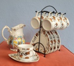 Suporte em metal com seis xícaras e pires para café em porcelana. Acompanha uma leiteira policromada de procedência diferente.