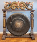 Gongo Tibetano em metal, muito antigo, estrutura em madeira, encimado com escultura de animal fantástico policromado, com o batedor.  Med.: 86x85cm.