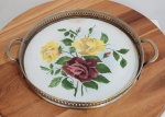 Bandeja redonda em porcelana, anos 1960, borda em metal vazado com pegas. Med.: 23cm de diâmetro.