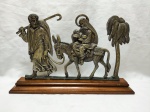 Escultura em bronze, representando "A fuga para o Egito", da Sagrada Família. Base retangular em madeira. Medindo 40cm x 25,5cm de altura.