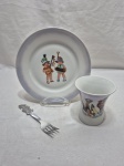 Kit infantil composto de prato e copo em porcelana e garfo em aço inox. Medindo o prato 20cm de diâmetro.