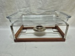Travessa retangular em vidro temperado e rechaud em madeira com acabamento em aço inox. Medindo o rechaud 25cm x 20cm x 12,5cm de altura, travessa 39,5cm x 23,5cm x 5cm de altura, com pequeno bicado.