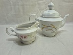 Lote de bule e leiteira em porcelana Real, sendo uma trigo e uma floral. Medindo o bule 17cm de altura.