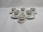 Jogo de 6 xícaras de café 2 goles com 5 pires em porcelana Steatita com propaganda Plasser. Medindo 4cm x 4cm de altura.