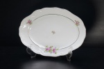 SCHMIDT- Pequena travessa em porcelana branca. Déc. 60, borda gomada. Adornada com rosas e folhagens esparsas. Frisos à ouro folha. Base e alças moldadas em volutas. Marca da Manufatura no fundo. (2 bicados na borda). Medidas: 33 x 22 cm.