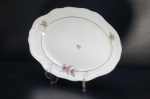 SCHMIDT- Pequena travessa em porcelana branca. Déc. 60, borda gomada. Adornada com rosas e folhagens esparsas. Frisos à ouro folha. Base e alças moldadas em volutas. Marca da Manufatura no fundo. (bicado na borda). Medidas: 37 x 24 cm.
