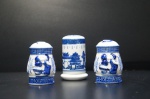 Três peças para servir em porcelana, sendo:a) Paliteiro adornado com linha oriental nas tonalidades azul e branca. Alt. 8 cm.b) Saleiro e pimenteiro, sortidos, adornados com imagem de casal holandês na tonalidade azul e branco. Alt. 7 cm.