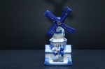 Estatueta de moinho com casal holandês, em porcelana, dita da cidade de Delft - Holanda, esmaltada com estanho, adornada na tonalidade azul cobalto sobre fundo branco. É dito um símbolo popular na cidade desde o século XVII. Marcada no fundo. Medidas: 15 x 7 x 6 cm.