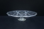 Grande prato para bolo de pé alto, executado em vidro lapidado com triliças e palmas, haste sextavadas. Borda imitando pétalas. ALT.