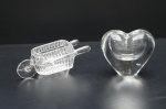Duas peças decorativas executadas em cristal lapidado, translúcido e incolor, sendo:Carrinho de mão e peso para papel em formato de coração, com vazado.Maior comp. 13 cm (coração).