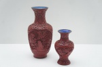 Dois imponentes vasos (2) orientais, confeccionados em laca vermelha, adornados com volutas, flores e folhagens em relevo. Parte interna em metal esmaltado na tonalidade azul royal. Tamanhos diferentes. Alt. 13 e 20 cm.