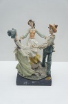Giuseppe Armani (1935-2006) - Rara e valiosa escultura italiana "A Ciranda" (Roda da Dança), assinada pelo renomado mestre Giuseppe Armani e produzida para a Florence Sculture d'Arte (Estilo Capodimonte). A obra é feita em resina de porcelana, com delicada pintura manual e policromia suave, retratando três figuras em trajes de época com notável realismo e fluidez. Datada provavelmente do final do Século XX, repousa sobre uma elegante base de mármore preto. Medidas: 27 x 18 x 18 cm.