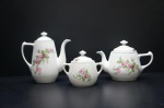 REAL (1943-1972) - Parte de conjunto para chá e café, confeccionados em porcelana branca, moldada na pasta, déc. 50. Adornado com ramos de rosas em rica policromia. Borda a e motivos filetados na tonalidade verde. Marca da Manufatura no fundo. Sendo: Bulê para chá, bulê para café e açucareiro. Maior alt. 19 cm. (pequeno bicado na borda).
