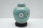 Vaso Bojudo Chinês  Luxo da Arte da República (Século XX) Magnífico Vaso Bojudo (Ginger Jar) é uma peça de colecionador que irradia a opulência da arte cerâmica chinesa; a cor predominante do fundo é um rico esmalte verde-água (turquesa), servindo de tela para a exuberante decoração Famille Rose em policromia; o adorno é denso, com um fundo brocado de arabescos e medalhões com caracteres auspiciosos (Wàn Shòu, Longevidade), demonstrando alta maestria; a história da peça situa-a no início a meados do Século XX (Período da República), quando foi produzida com a marca apócrifa Qianlong como fina homenagem ao estilo imperial do Século XVIII. Alt. 24 cm.