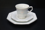 SCHMIDT- Gracioso Trio para chá porcelana branca,ornamentado com barrado azul bebê e fino adorno de flores esmaltadas na tonalidade branca e rosa. Pires e prato para lanche oitavados, borda com friso prateado. (Base da xícara com quebrado. Marcado no fundo. Diâm. 19 cm.