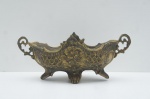 Elegante Centro de Mesa ou fruteira antiga, confeccionada em bronze maciço. A peça apresenta um design ornamental característico do Estilo Vitoriano (c. 1900), com laterais e pés ricamente trabalhados. Destaca-se o alto-relevo floral na parte central e as alças vazadas.