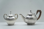 Sheffield Plate - Bulê e Açucareiro em metal espessurado à prata, contrastado. Bojo gomado, adornado com caneluras. Pega em madeira nobre. Marca da Manufatura no fundo. Bulê alt. 18 cm / Açucareiro alt. 16 cm.
