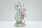 Graciosa escultura francesa confeccionada em biscuit, representando Cena de Casal galante dançando com trajes de época, adornado em rica policromia e fios à ouro folha. Alt. 27 cm.