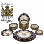 PARAGON - INGLATERRA - FORNECEDORA OFICIAL DE PORCELANAS PARA A RAINHA ELIZABETH II - Lendário e magnífico aparelho de jantar e sobremesa, peças finamente executadas em nobre porcelana de ossos de excepcional qualidade e renomadíssima manufatura, adornadas por linda ornamentação floral, bela tonalidade azul cobalto e riquíssimos filetes e coberturas á ouro. Composto por 22 pratos rasos para jantar, 10 pratos rasos para sobremesa, 10 pratos rasos para aperitivo/entrada, 10 pratos fundos para sopa, 1 Bowl, 3 travessas ovais e 1 prato para bolo. Perfeito estado de conservação. Inglaterra, primeira metade do Século XX. Bowl mede 6 cm de altura x 26 cm de diâmetro da borda, travessa maior mede 46 x 36 cm, pratos para aperitivo medem 15,5 cm de diâmetro e para jantar 25,5 cm cada. Oportunidade única! Nota histórica: A manufatura Paragon recebeu o Royal Warrant  Mandado Real Britânico  que conferia o título de fornecedora oficial de porcelanas para Sua Majestade a Rainha Elizabeth II.O Royal Warrant é uma honraria concedida pela Casa Real do Reino Unido a fabricantes que fornecem produtos de excelência à família real por longos períodos. Essa distinção permite o uso do brasão real e atesta o prestígio, a tradição e a alta qualidade da manufatura.