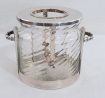 ST. JAMES, Champanheira confeccionado em metal espessurado a prata, alças laterais trançadas, tampa e suporte para garrafa com recipiente em vidro moldado em gomos. Med. 18 x 26 cm entre alças.