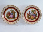 LIMOGES- Pendant de pratos em porcelana francesa , decorada ao centro  por cena galante ao gosto do século XVIII, executada em estampagem policromada, inspirada em composição de Jean-Honoré Fragonard, representando "Cena Galante". Bordas e faixas em tons marfim e grená com florais e frisos dourados.Marcada D.R.B..'Limoges - France' - Gout de Ville. Med. 19 cm diâmetro cada.
