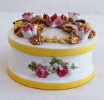 VIEIRA DE CASTRO - Porta joias em formato oval em porcelana , decorada na lateral com flores e frisos dourados. Tampa com flores e folhagens em alto relevo em policromia e farta douração. Pequenas perdas na folhagem. Med. 9 cm alt x 11 cm diâmetro.