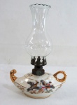 Gracioso lampião à querosene em porcelana, decorado com aves em douração, com manga em vidro translúcido. Med. 21 cm altura.
