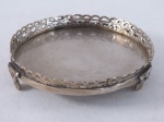 Salva redonda em metal espessurado a prata, decorada ao fundo com volutas , galeria vazada em volutas e três pés em garra. Med. 3 cm alt x 14 cm diâmetro.